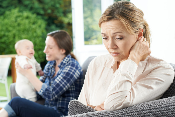 sad childless woman looking at happy woman with baby